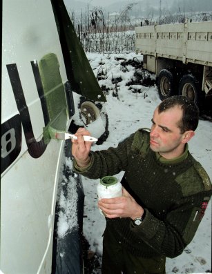 En norsk soldat maler over FN-logoen.